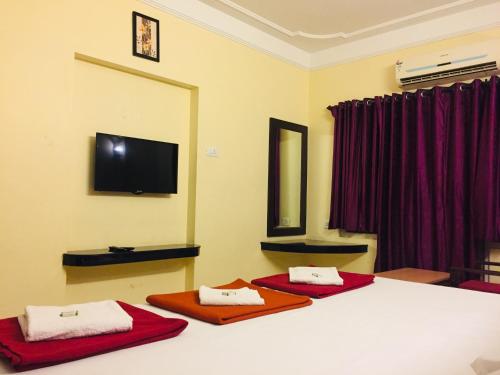a bedroom with two beds and a flat screen tv at Hotel Sun Rock in Kanyakumari