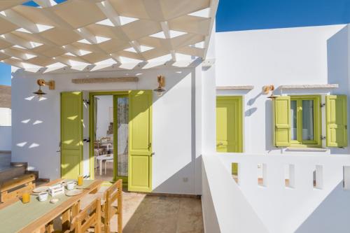 a patio with green shutters and a table and chairs at Parathinalos Beach House in Livadi Astypalaias