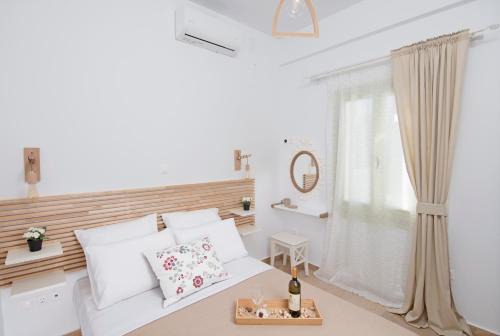 a white bedroom with a bed and a window at Parathinalos Beach House in Livadi Astypalaias
