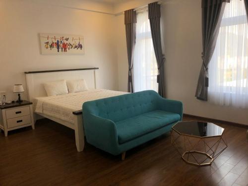 a bedroom with a bed and a blue couch at Ngoc Lan Hotel and Coffee in Ðưc Trọng