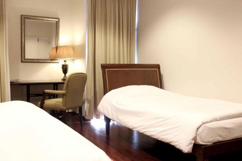 Habitación de hotel con 2 camas, escritorio y espejo. en Samsen Suites/ 2 Br Suites for less, en Bangkok