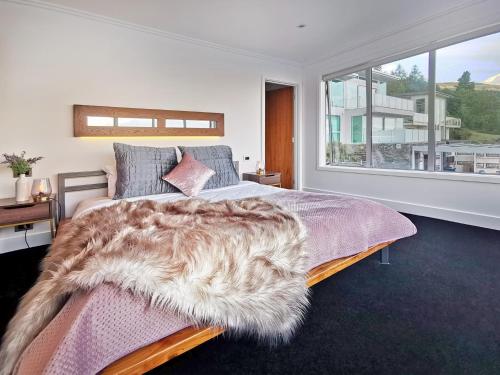 ein Schlafzimmer mit einem Bett mit einem großen Fenster in der Unterkunft Luxe Home on the Hill in Queenstown