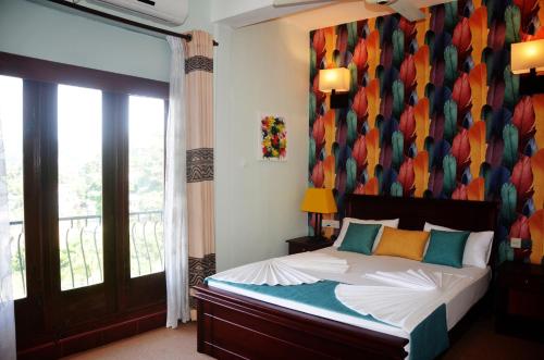 a bedroom with a bed and a balcony with a window at Blinkbonnie Inn in Kandy