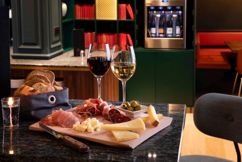 a plate of meat and cheese and two glasses of wine at Hotel Le Colombier in Obernai