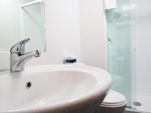 a white bathroom with a sink and a toilet at Tetra Serviced Apartments by Castle in Auckland