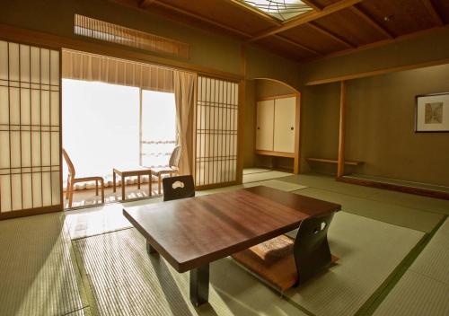 a room with a wooden table and a large window at Atami Kinjokan in Atami