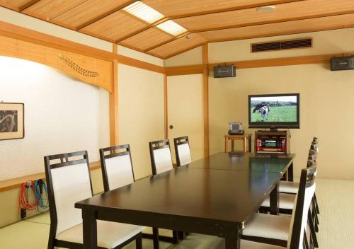 a dining room with a table and chairs and a tv at Atami Kinjokan in Atami