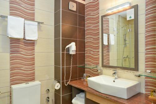 a bathroom with a sink and a toilet and a mirror at Hotel Hill in Jagodina