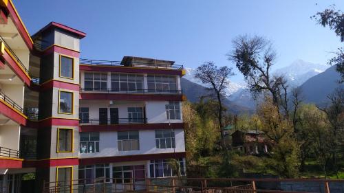 a apartment building with mountains in the background at Highland Village Resort in Dharmsala