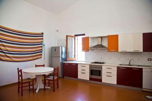 La cuisine est équipée d'une table, de chaises et d'un réfrigérateur. dans l'établissement villa francesca e cristina, à Ferruzzano