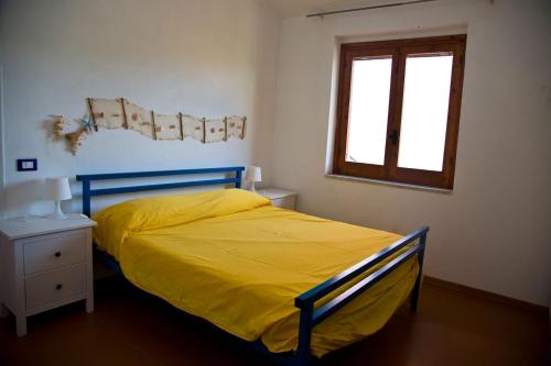 a bedroom with a yellow bed and a window at villa francesca e cristina in Ferruzzano