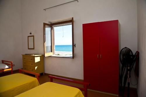 - une chambre avec 2 lits, une armoire rouge et une fenêtre dans l'établissement villa francesca e cristina, à Ferruzzano