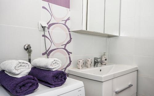 uma casa de banho com toalhas roxas sentadas em cima de um lavatório em Studio Blue Ivy em Plitvicka Jezera