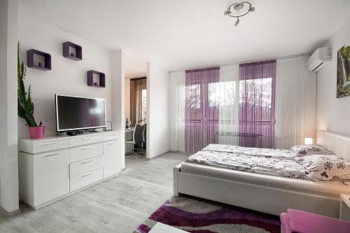 a white bedroom with a bed and a flat screen tv at Studio Blue Ivy in Plitvička Jezera