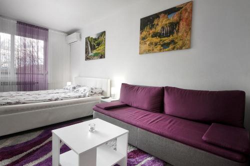 a living room with a purple couch and a bed at Studio Blue Ivy in Plitvička Jezera