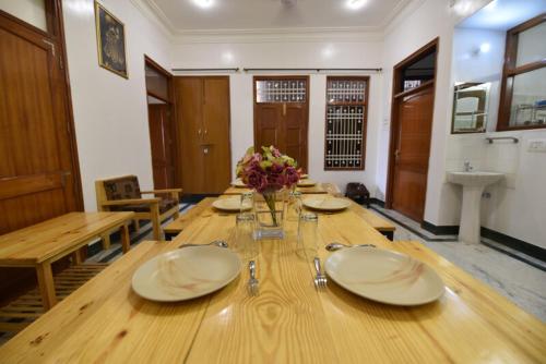 a large wooden table with plates and flowers on it at Balbir Niwas Guesthouse Homestay in Udaipur