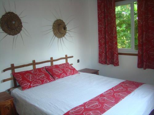 a bedroom with a bed with red pillows and two windows at Les Cottages de Bellevue Ecolodge in Port Vila