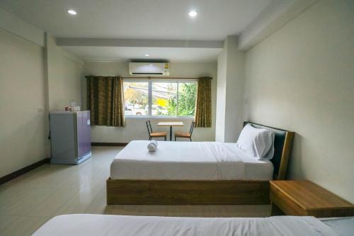 Schlafzimmer mit einem Bett, einem Tisch und einem Fenster in der Unterkunft DD Place in Suphan Buri