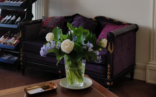 eine Vase mit Blumen auf einem Tisch vor einer Couch in der Unterkunft Hotel Bleu de Mer in Bordeaux