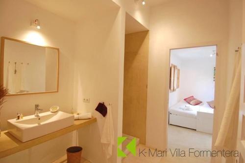 a bathroom with a sink and a mirror and a bed at K-Mari Villa Formentera in Playa Migjorn