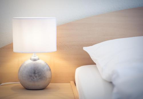 a lamp sitting on a table next to a bed at Hotel Altes Kurhaus in Baabe