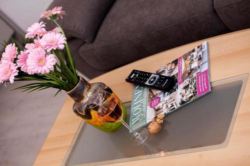 a vase of flowers on a table with a remote control at Ferienhaus Butterfly in Garmisch-Partenkirchen