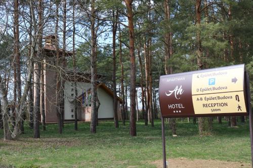 a sign in front of a house with a building at Apartman Hotel in Bük