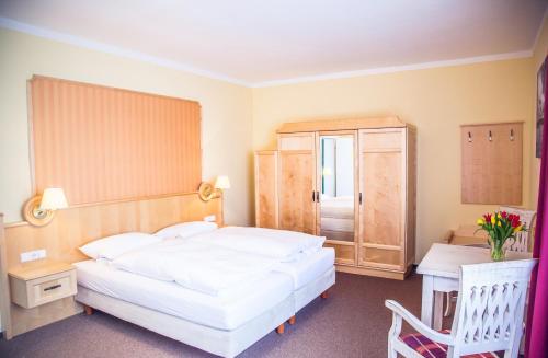 a bedroom with a large white bed and a desk at Hotel Altes Kurhaus in Baabe