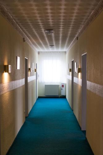 a hallway with a blue carpet and a window at Hotel Altes Kurhaus in Baabe