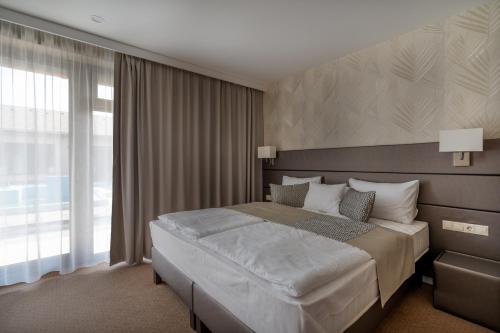 a bedroom with a large bed and a large window at DorEsz Wellness Panzió in Újhartyán