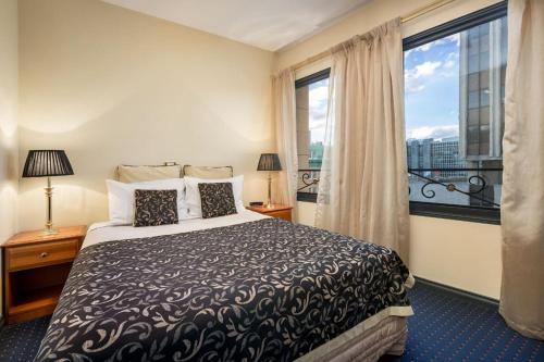 a bedroom with a bed and a large window at Quest Savoy in Hobart