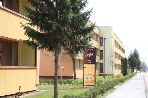 a tree in front of a building next to a street at Apartman Hotel in Bük