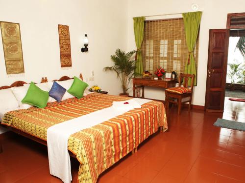 a bedroom with a large bed and a table at Soma Palmshore in Kovalam