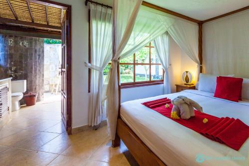 a bedroom with a bed with a stuffed animal on it at Villa Segara Murti - Stylish Beachfront Villa! in Banjar