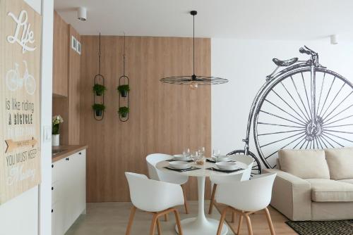 a dining room with a table and white chairs at CHILLIapartamenty - Bliżej Morza - BIKE in Kołobrzeg