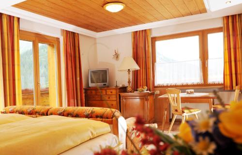 a bedroom with a bed and a desk and a table at Pension Alwin in Lech am Arlberg