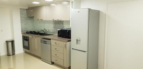 a kitchen with a white refrigerator in a room at 100m2 2 chambres 8 personnes - Grand parking et terrasse privée - Proche CDG-Parc expositions-Paris-Astérix-Disney in Villepinte