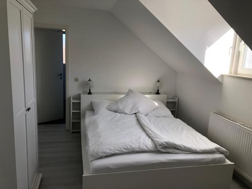 łóżko z białą pościelą i poduszkami w pokoju w obiekcie eifelTIME - Ferienwohnung w mieście Bad Münstereifel