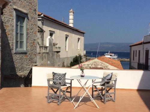 a table and chairs on a balcony with a lighthouse at Astraea in Hydra
