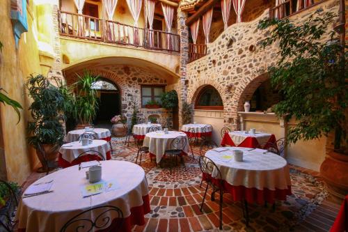 eine Terrasse mit Tischen und Stühlen in einem Gebäude in der Unterkunft Hotel Anticos Palathos in Orosei