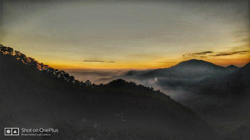 a sunset in the mountains with clouds in the valley at Green Roof Hotel in Nainital