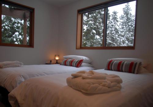 two beds in a room with two windows at Bears Den Mountain Lodge in Hakuba