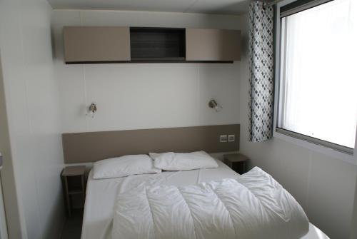 a white bed in a bedroom with a window at Sevservices à La Réserve in Gastes