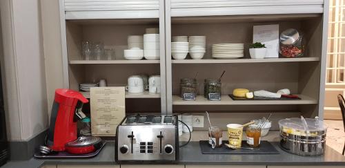 a kitchen cabinet with a coffee maker and dishes at Hotel De La Cite Rougemont in Paris