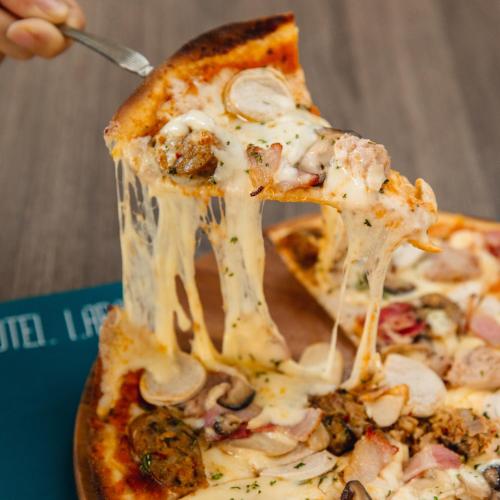 a person eating a slice of pizza with a spatula at Hotel Labaris Khao Yai in Mu Si
