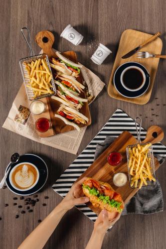 a table with a person holding a sandwich and french fries at Hotel Labaris Khao Yai in Mu Si