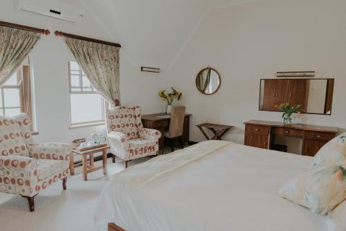 a bedroom with a bed and two chairs and a desk at Cana Vineyard Guesthouse in Paarl