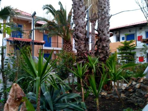 a garden in front of a building with palm trees at 9 Musses Hotel Apartments in Skala Mistegnon