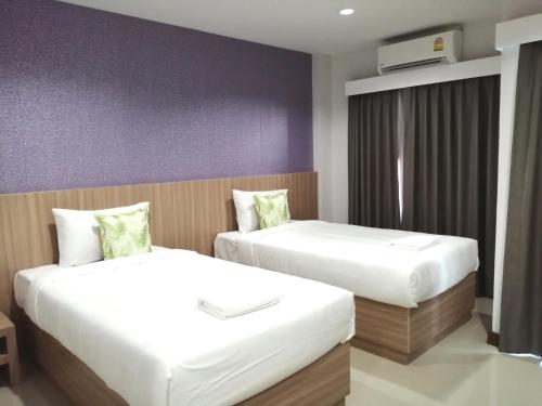 a bedroom with two beds and a purple wall at The Like hotel in Udon Thani