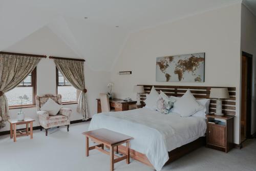 a bedroom with a large bed and a chair at Cana Vineyard Guesthouse in Paarl